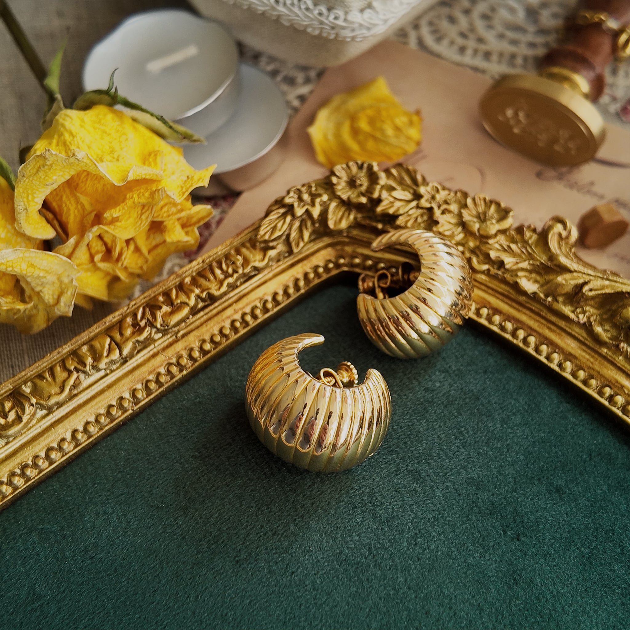 An angled view of the gold sculptural earrings, highlighting the beautiful, volumetric "croissant" twist that defines this classic piece of 70s jewelry design.
