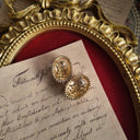 The reverse side of the earrings, showing the signature scrollwork texture that identifies them as authentic 1928 Jewelry, a mark of their vintage heritage.