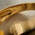 This 23k gold-plated ring features a square band set with round glass diamonds, while the band itself is plain gold with a simple geometric design. The inner ring bears the "23ktp" stamp.