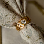 This 23k gold-plated ring features a round glass diamond set in a single piece, with the band openwork engraved with delicate patterns. It's a vintage ring with a retro style, featuring a gold band, 23k gold plating, and a glass diamond.
