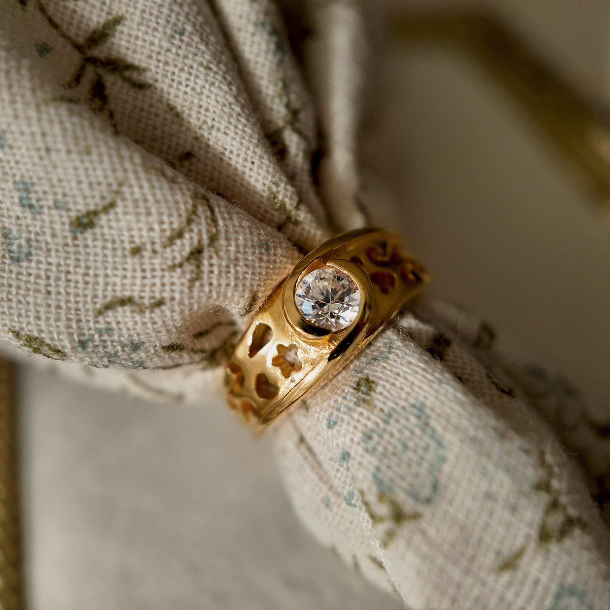 This 23k gold-plated ring features a round glass diamond set in a single piece, with the band openwork engraved with delicate patterns. It's a vintage ring with a retro style, featuring a gold band, 23k gold plating, and a glass diamond.