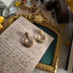 An angled view of the 1970s Trifari statement earrings, highlighting the contrast between the regal, fan-like filigree and the modern, bohemian ring.