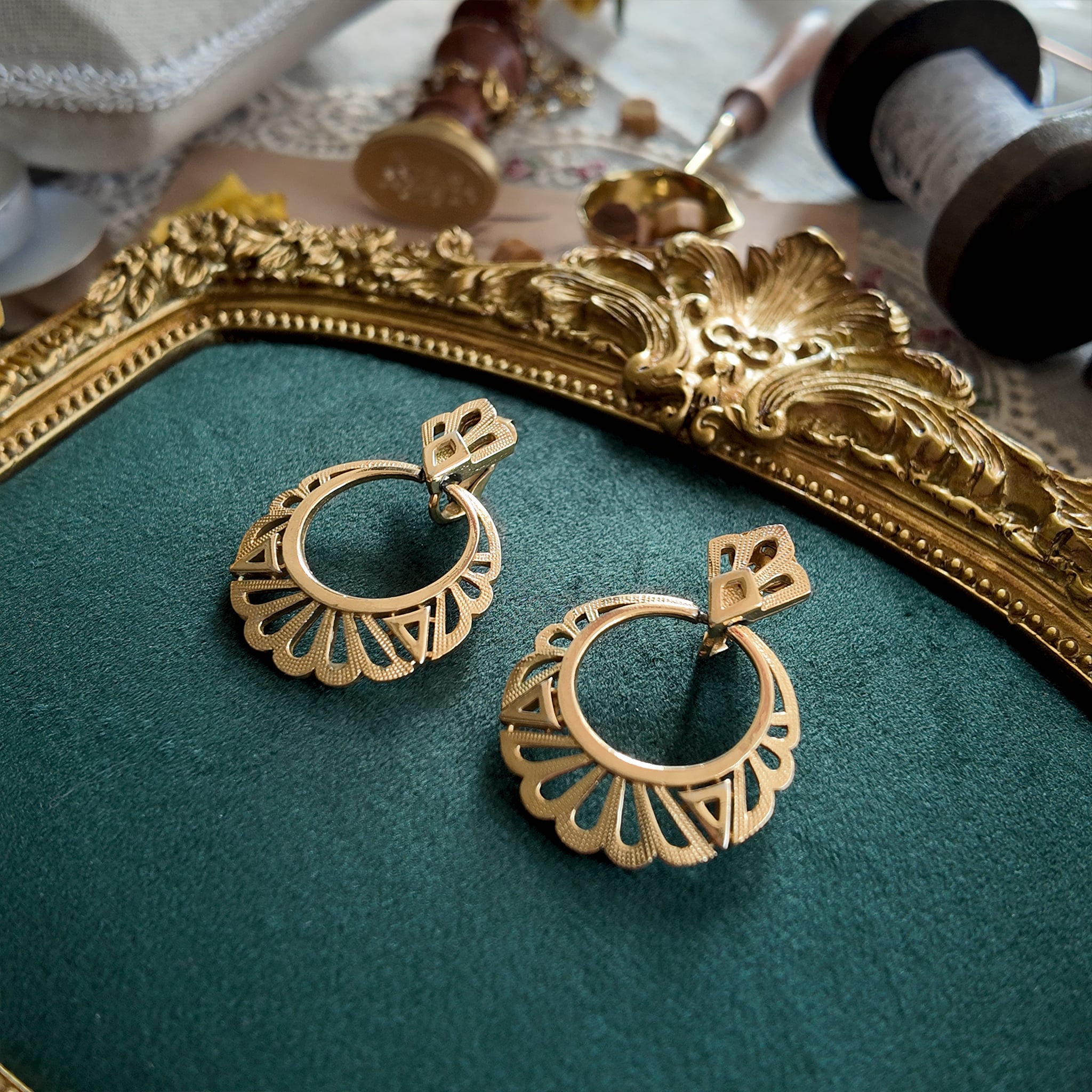 An angled view of the 1970s Trifari statement earrings, highlighting the contrast between the regal, fan-like filigree and the modern, bohemian ring.