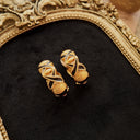 Showcasing the details of the front of the matte gold clip-on earrings and the enamel technique.