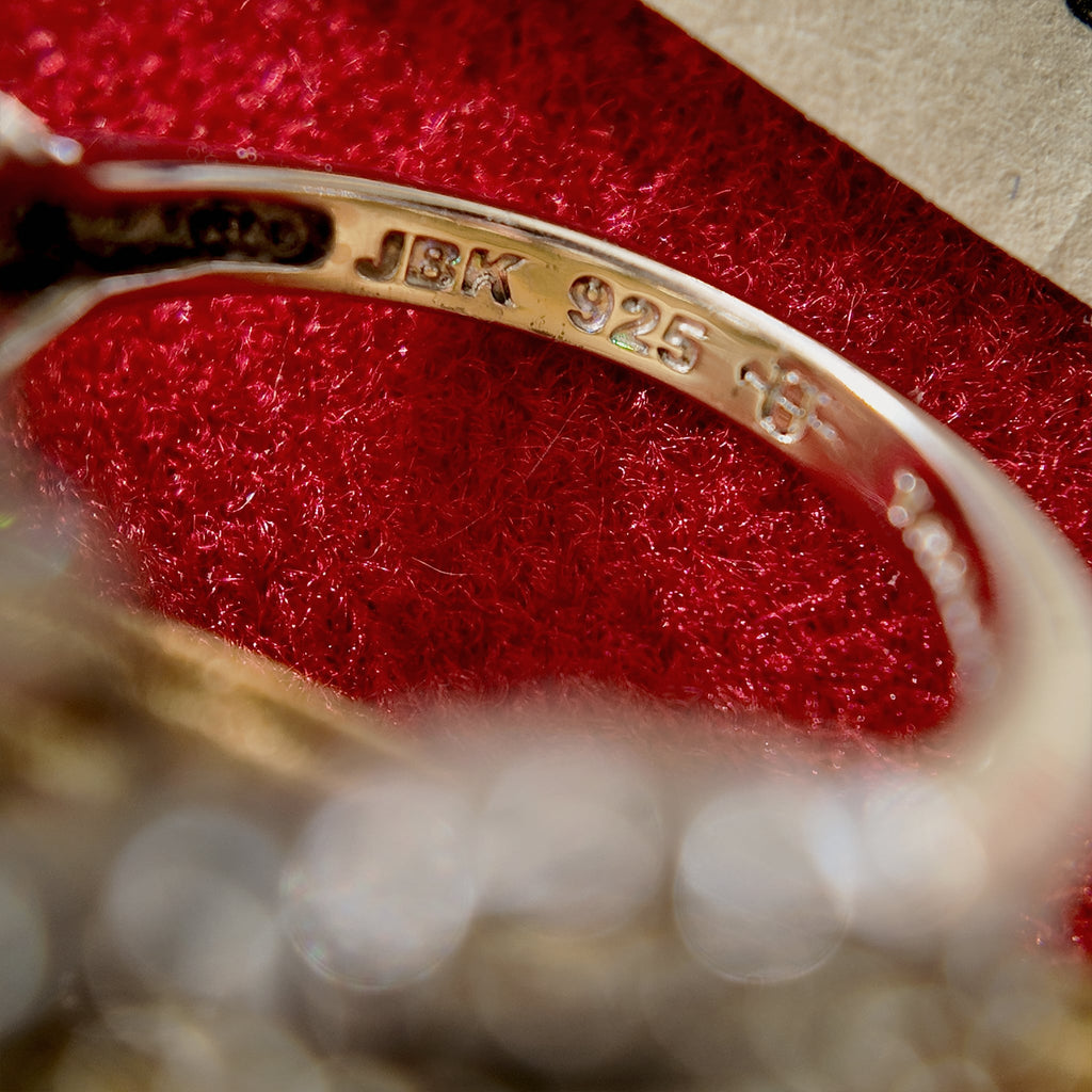 The high-magnification lens reveals the steel stamp on the inner band of the ring, which reads "JBK 925," signifying the official collaboration certification between Camrose & Kross and JBK, as well as the material certification of 925 silver.