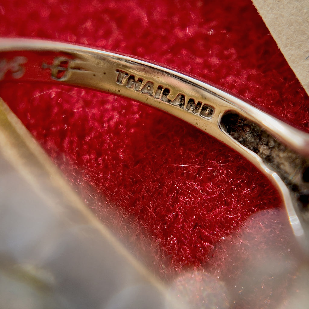 The high-powered lens reveals the steel stamp on the inner band of the ring, which reads "Thailand," indicating that the ring was made in Thailand.