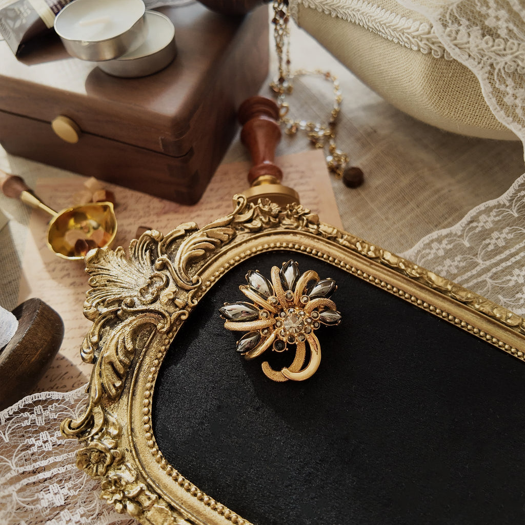 This vintage maple leaf-shaped jewelry brooch is from the brand "HOLLICRAFT." It features a gold-plated maple leaf design inlaid with obsidian and grey-black rhinestones. Like a castle in the desert, it's a classic piece combining gold and black.