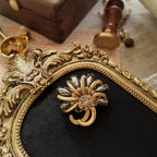 An obsidian brooch, featuring a marquise-shaped obsidian stone set in a gold brooch. Obsidian is a special type of stone with a metallic-like surface. Its deep color contrasts sharply with the gold.