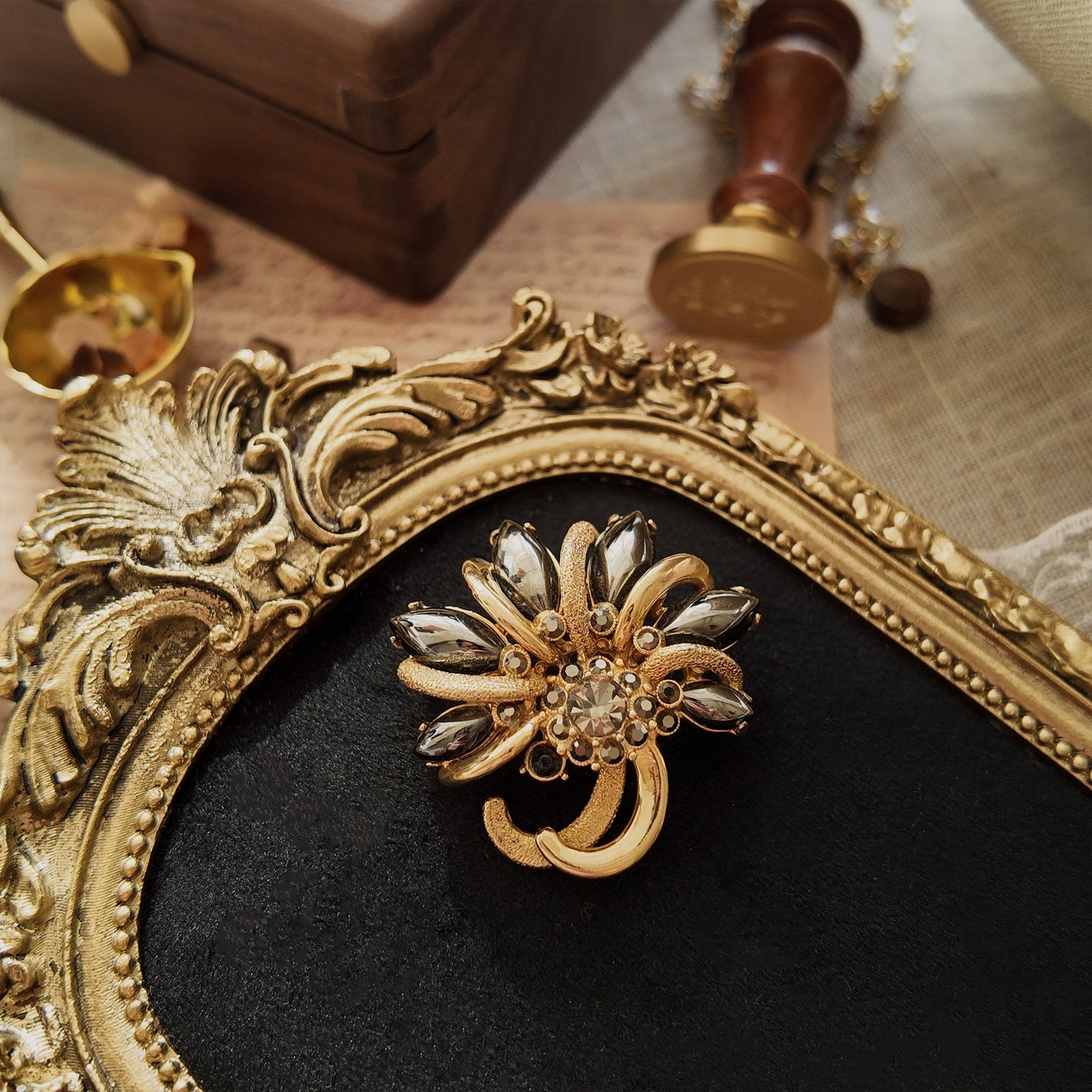 An obsidian brooch, featuring a marquise-shaped obsidian stone set in a gold brooch. Obsidian is a special type of stone with a metallic-like surface. Its deep color contrasts sharply with the gold.