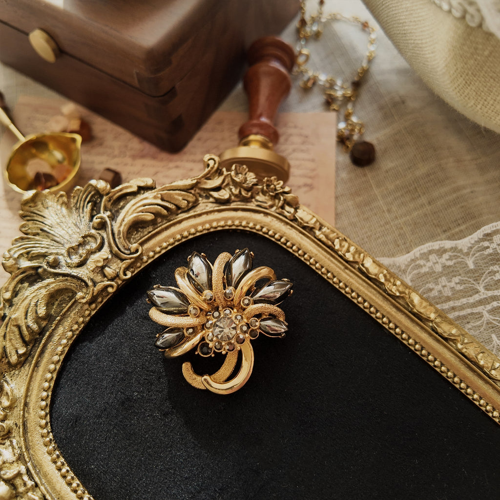 A vintage gold and black brooch with a unique design from the 1950s.