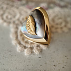 The black mother-of-pearl pendant features a small copper leaf. A botanical piece, reminiscent of vintage times.