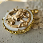 A vintage gold warrior pendant, inlaid with white mother-of-pearl, featuring reconstructed vintage accessories.