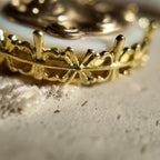 The gold lucky charm features openwork patterns on the sides, a classic floral design.