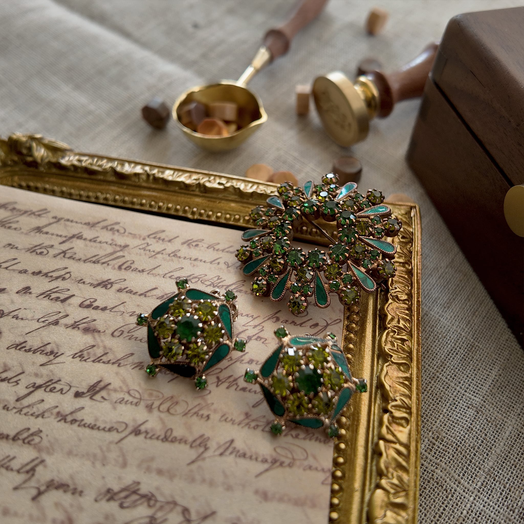 A vintage enamel brooch set with an emerald green ring of rhinestones resembles a bursting firework, and the set also includes a pair of round clip-on earrings. Both pieces are composed of toned enamel and high-quality rhinestones and are from the brand WEISS.