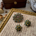 A green vintage jewelry set, featuring a green rhinestone brooch with pearlescent enamel inlay.