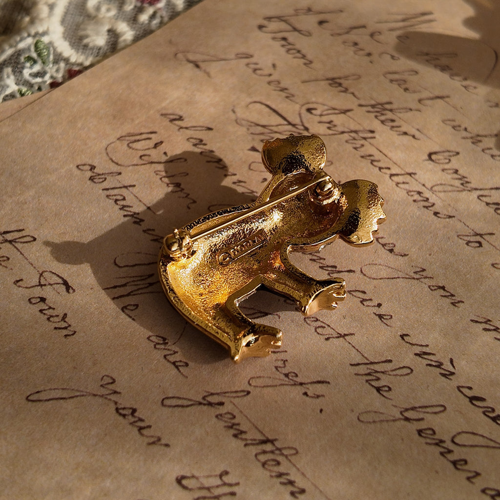 This koala brooch from D'orlan lies in the sunlight, showcasing the koala's back and highlighting the brand name stamped on the back panel—a hallmark of authenticity.