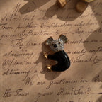 This koala brooch from D'orlan lies in the sunlight, showcasing this side of the koala and highlighting its adorable expression.