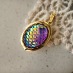 Laser-engraved fish-scale photo box pendant, oval metal outline, gold back plate. Three-dimensional sculpted West German glass jewelry, purple iridescence, fish-scale shape. Vintage ocean-themed jewelry, legend of the golden mermaid.
