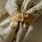A gold ring with A gold ring set with two rows of glass diamonds set through a floral fabric