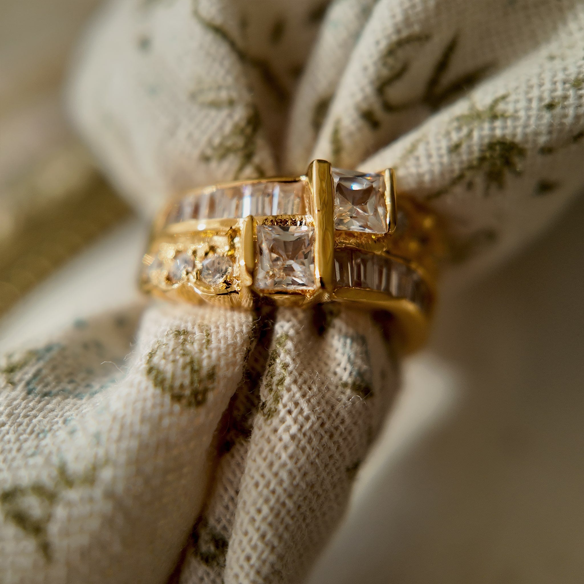 A gold ring with A gold ring set with two rows of glass diamonds set through a floral fabric