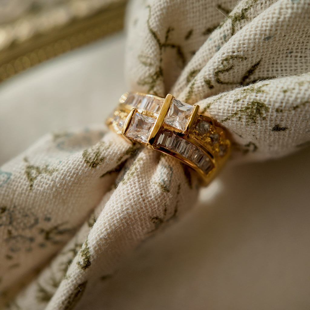 A gold ring with A gold ring set with two rows of glass diamonds set through a floral fabric