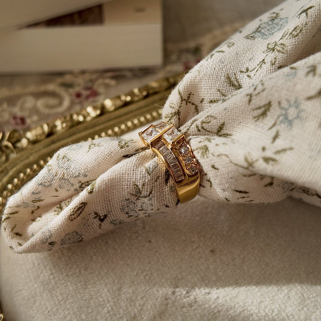 A gold ring with A gold ring set with two rows of glass diamonds set through a floral fabric side view