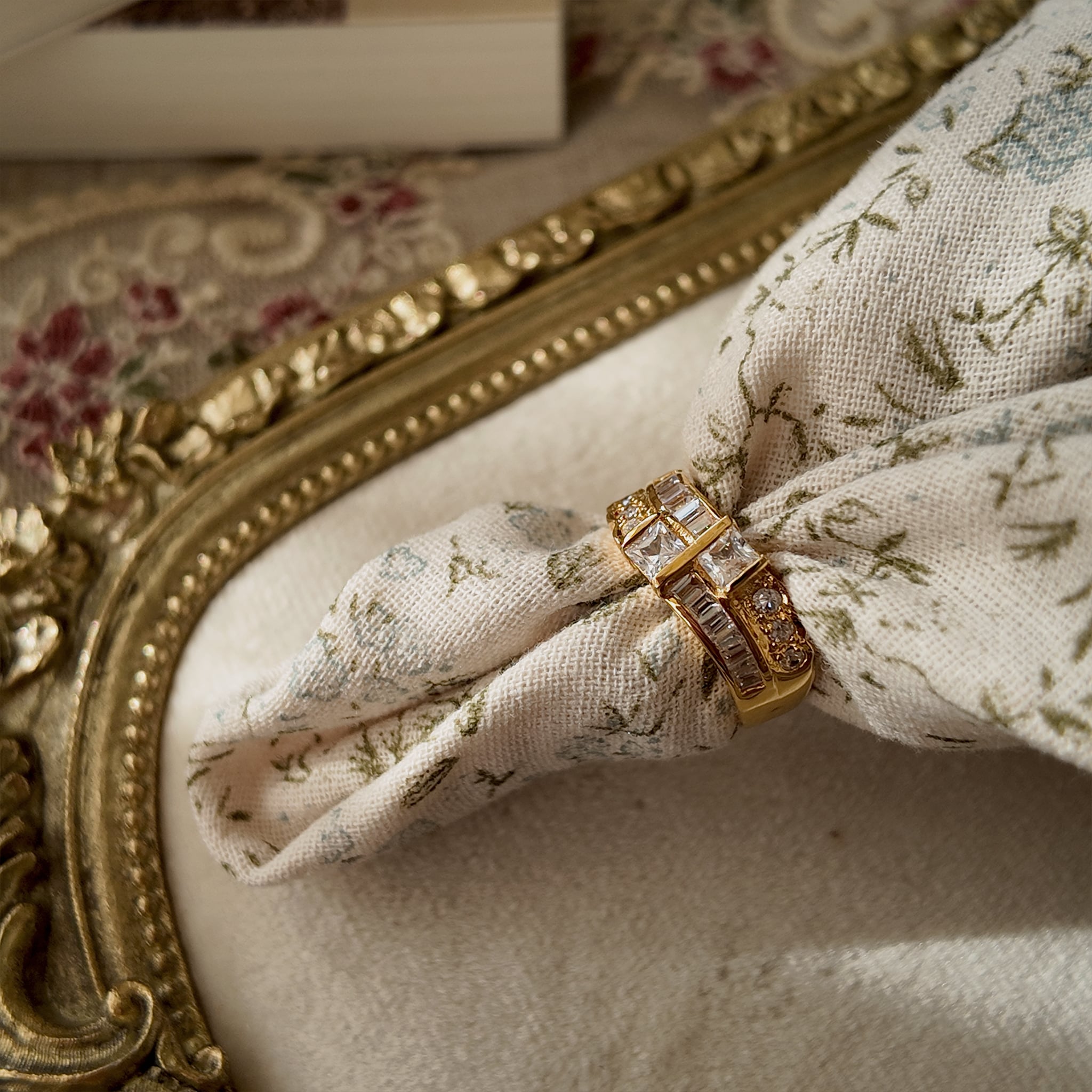 A gold ring with A gold ring set with two rows of glass diamonds set through a floral fabric side view