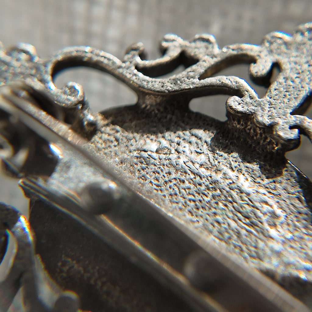 This image showcases the back of the opal brooch under high magnification, revealing subtle hammered textures and the finishing on the metal parts.