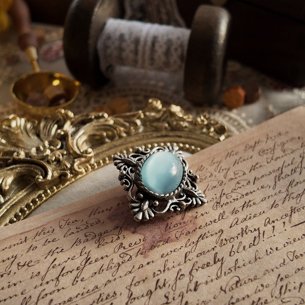 A close-up side view of the imitation opal brooch, showcasing the thickness of the opal protrusions and the details of the brooch's engraving.