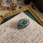 A silver cloisonné brooch set with emerald gemstones; a close-up side view shows the vintage brooch from a side perspective.