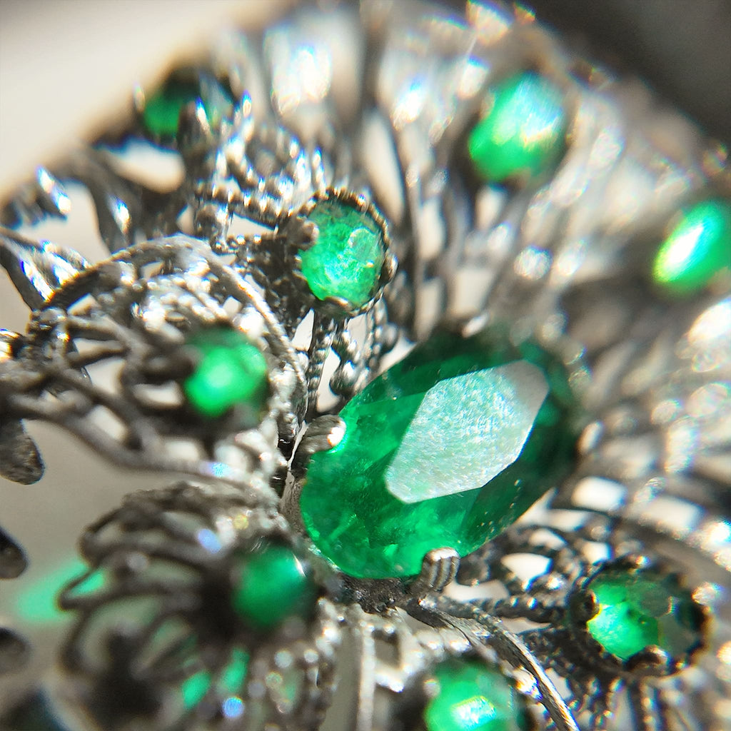 A close-up of the silver cloisonné brooch reveals more details of the emerald gemstone.