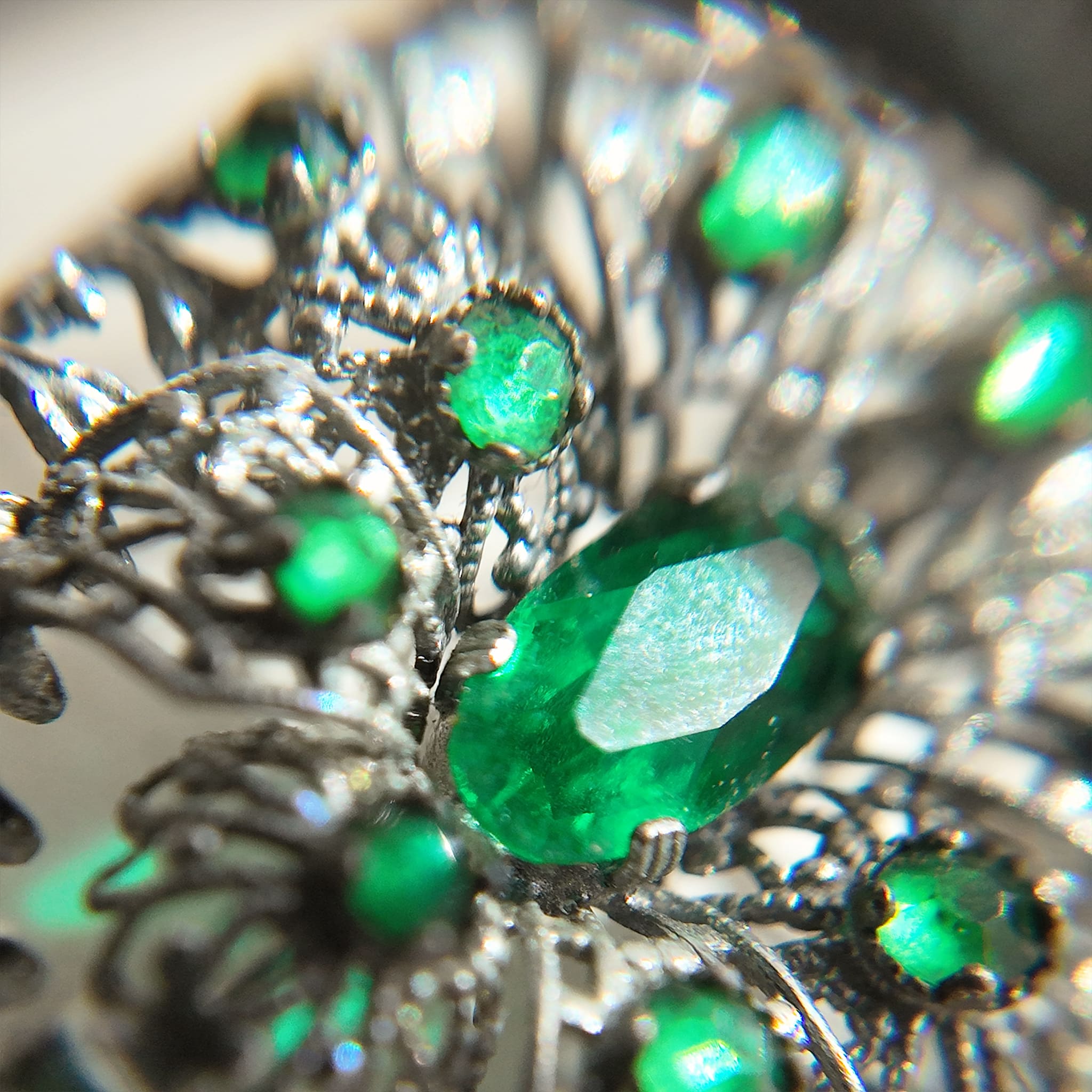 A close-up of the silver cloisonné brooch reveals more details of the emerald gemstone.