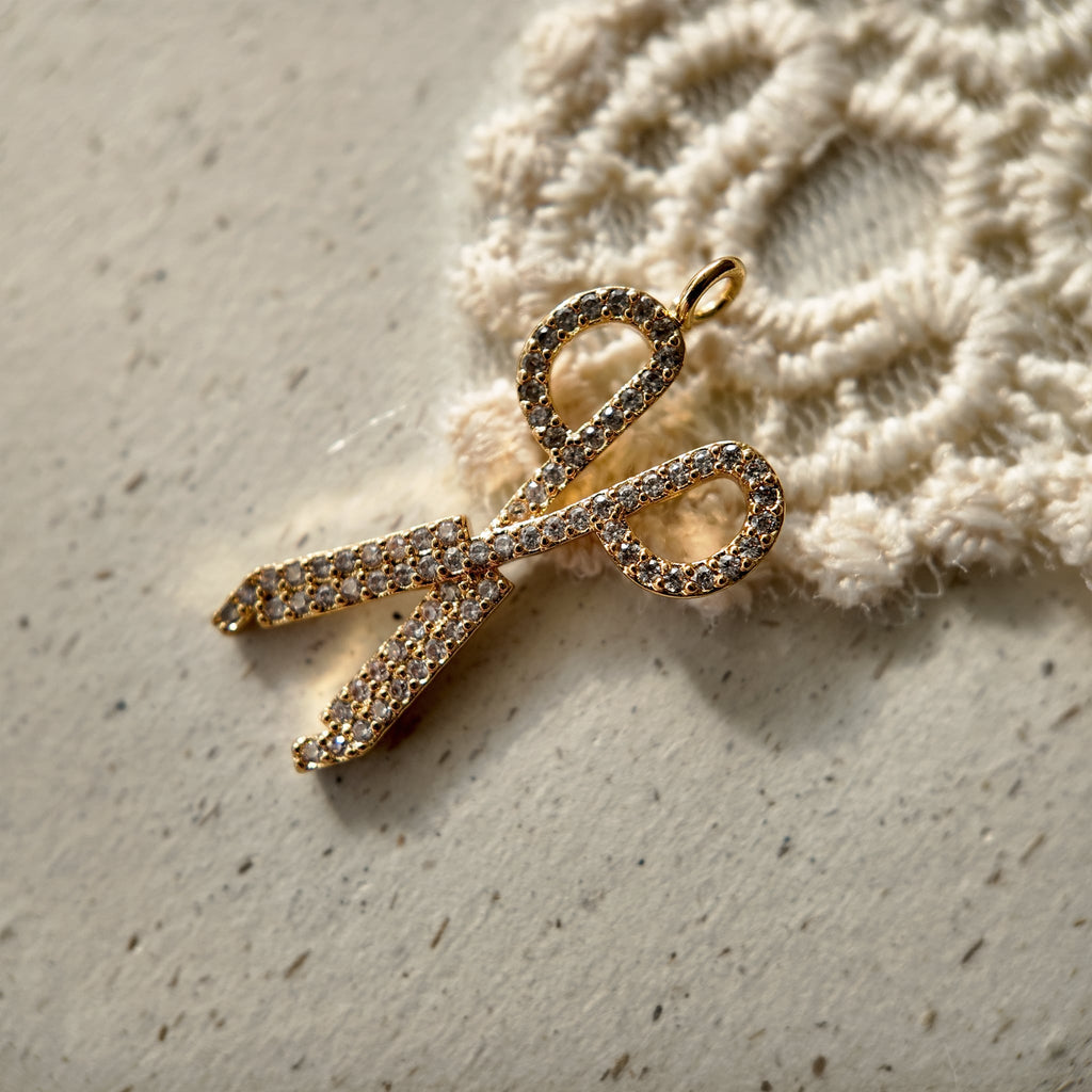 A gold scissor-shaped pendant, set with sparkling rhinestones.