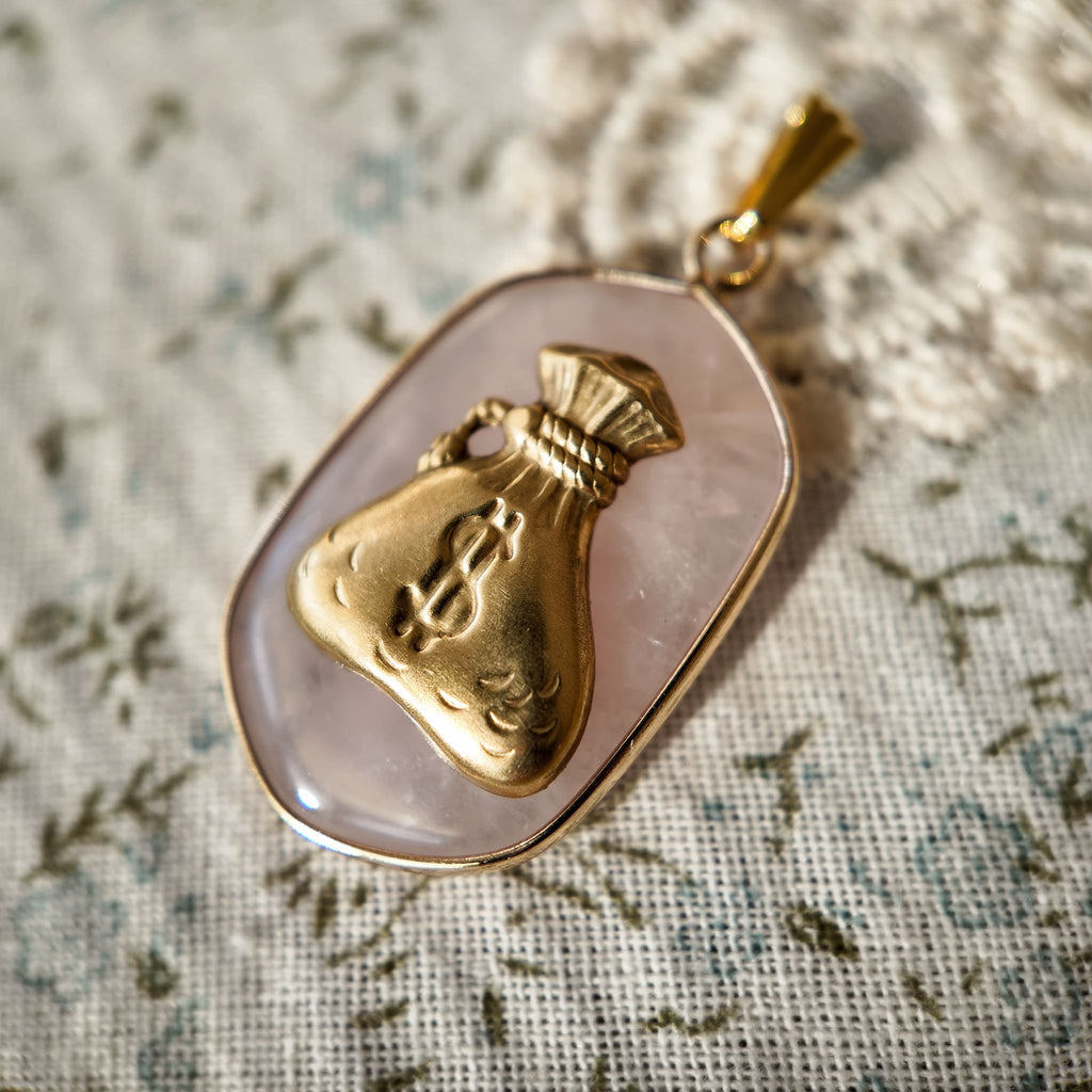 A cute money bag pendant paired with a rhombus-shaped pink crystal. A vintage-sweet pink jewelry piece; the vintage pendant evokes a retro era.