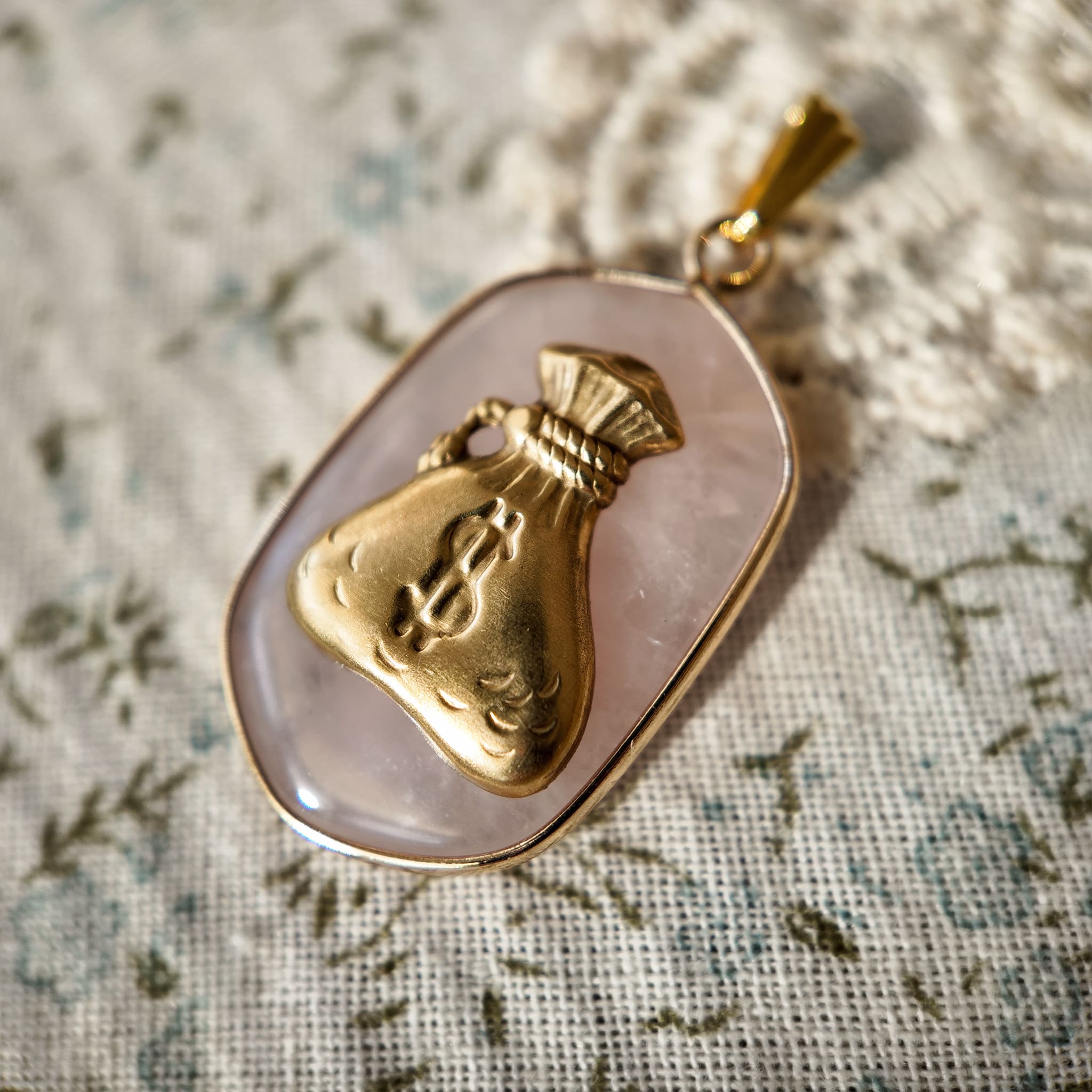 A cute money bag pendant paired with a rhombus-shaped pink crystal. A vintage-sweet pink jewelry piece; the vintage pendant evokes a retro era.
