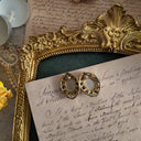Showing the back of the vintage earrings, made of metal with a vintage patina and gold trim.