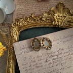 Showing the back of the vintage earrings, made of metal with a vintage patina and gold trim.