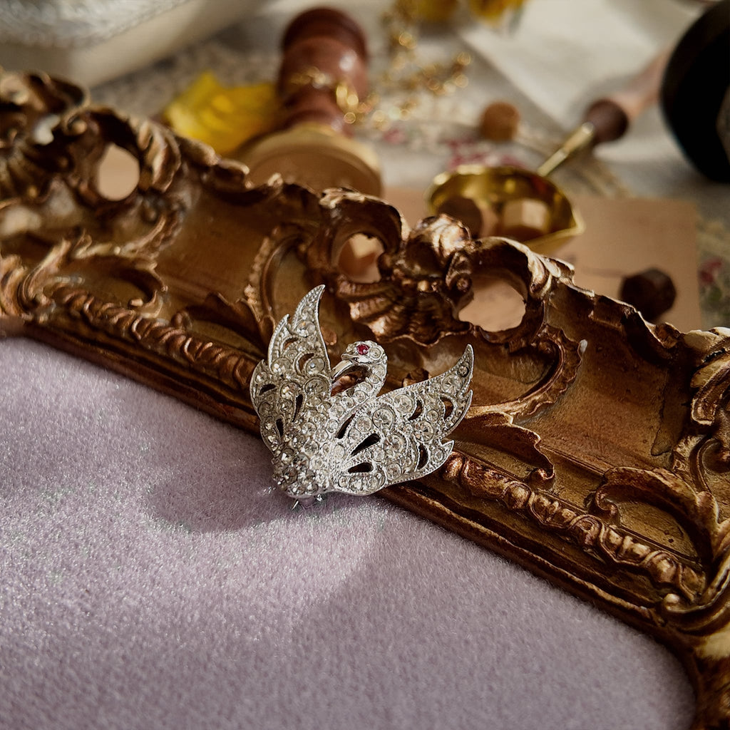A small silver rhinestone brooch. The vintage swan design exudes luxury; a sparkling brooch.