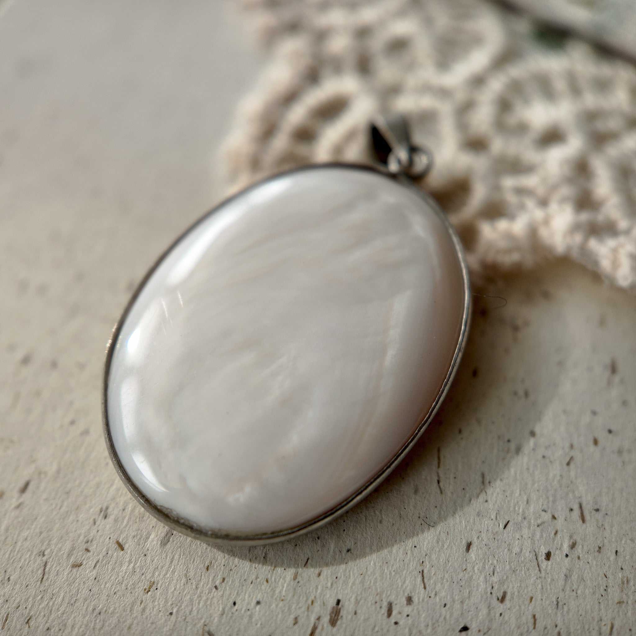 The back of the mother-of-pearl carved pendant features the pearly luster of a pearl, creating a smooth, satin-like finish.