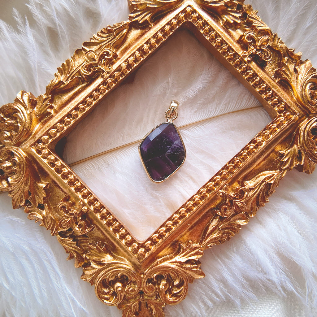 The reverse side of the upcycled amethyst charm, showcasing the facets on the back of the stone that allow light to pass through, and the handcrafted assembly.
