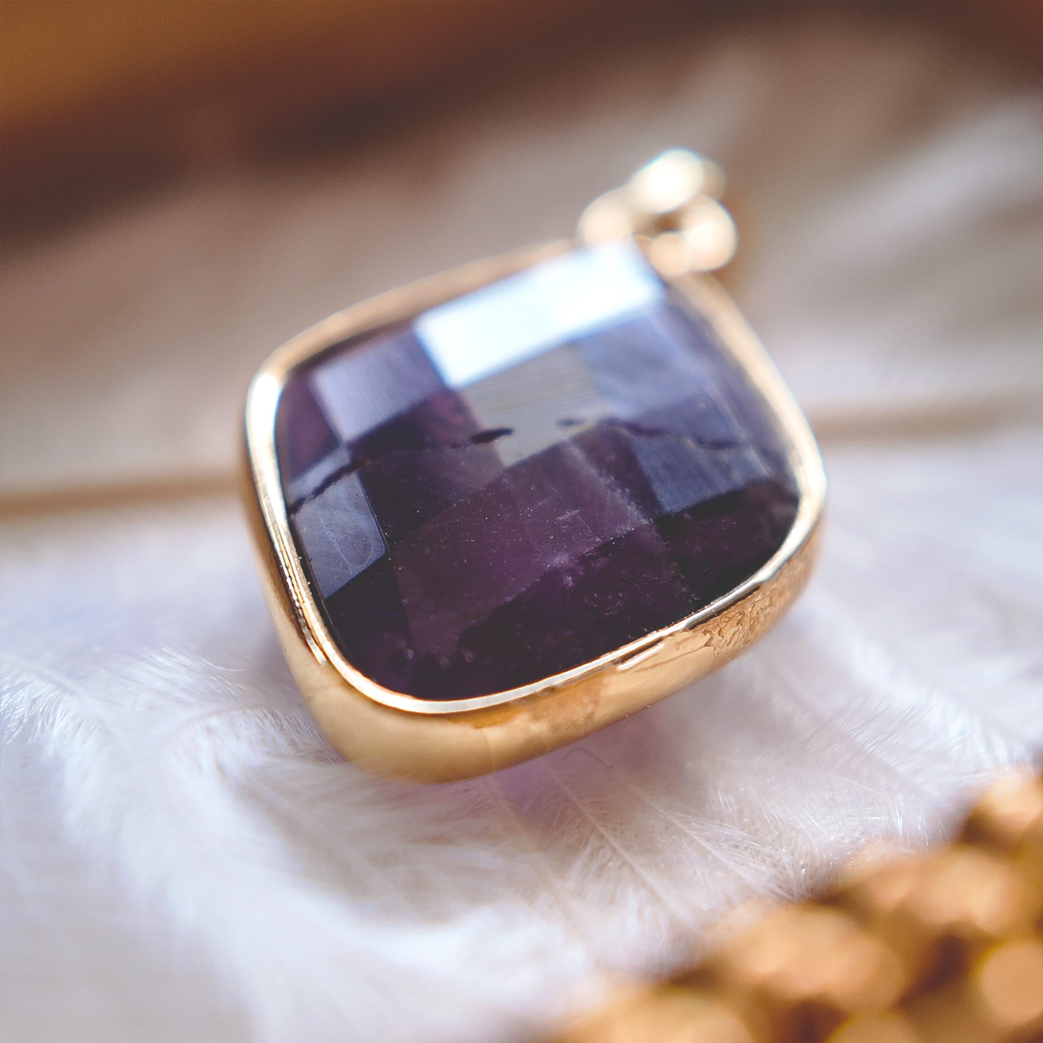The reverse side of the upcycled amethyst charm, showcasing the facets on the back of the stone that allow light to pass through, and the handcrafted assembly.