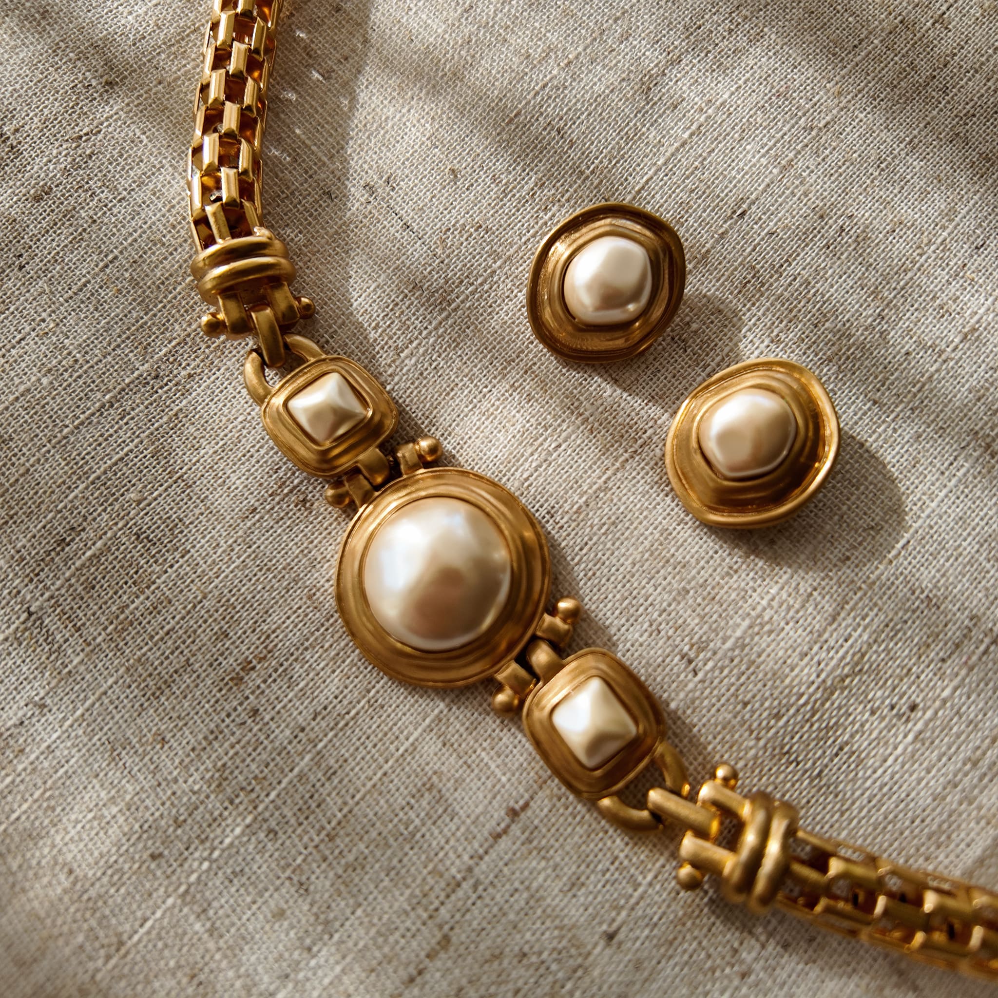 A macro shot detailing the unique, architectural plait design of the necklace chain and the organic, imperfectly perfect surface of a baroque pearl.