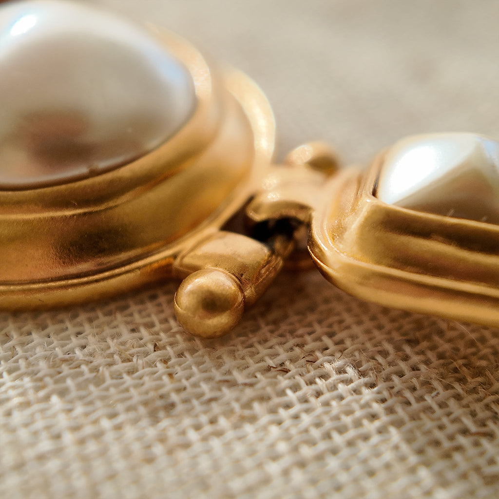 A macro shot detailing the unique, architectural plait design of the necklace chain and the organic, imperfectly perfect surface of a baroque pearl.