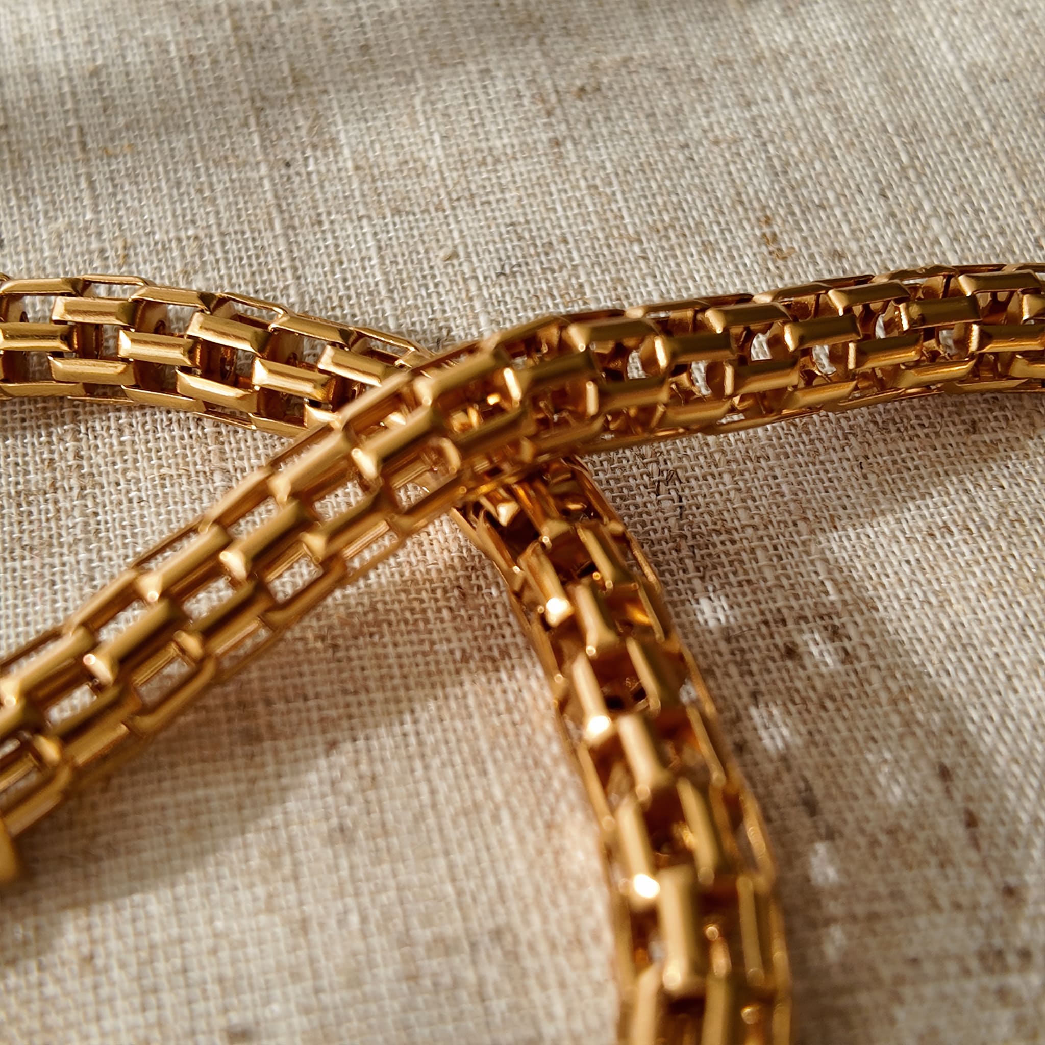 A macro shot detailing the unique, architectural plait design of the necklace chain and the organic, imperfectly perfect surface of a baroque pearl.