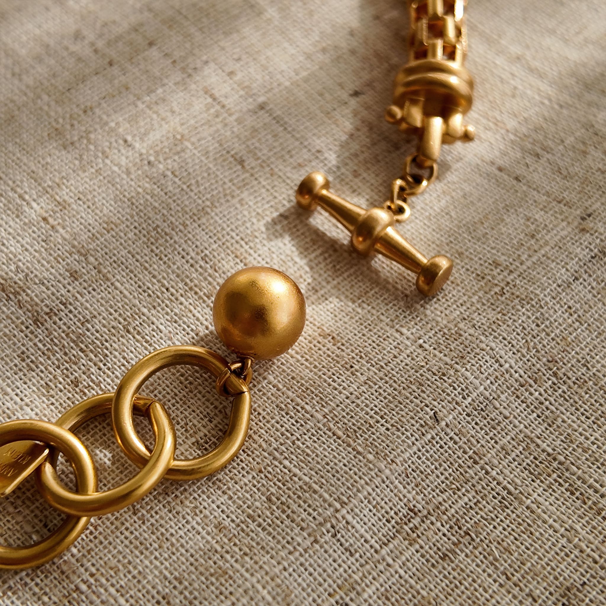 A macro shot detailing the unique, architectural plait design of the necklace chain and the organic, imperfectly perfect surface of a baroque pearl.