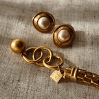 A detailed photo of the authentic Anne Klein signatures: the iconic lion head logo hang tag on the necklace and the signature "AK" hammered texture on the reverse.