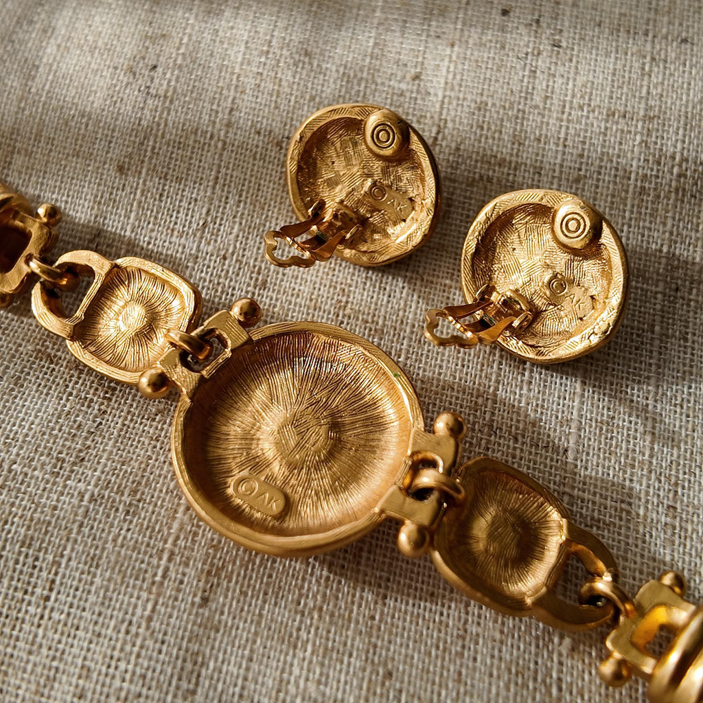 A detailed photo of the authentic Anne Klein signatures: the iconic lion head logo hang tag on the necklace and the signature "AK" hammered texture on the reverse.