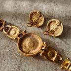 A detailed photo of the authentic Anne Klein signatures: the iconic lion head logo hang tag on the necklace and the signature "AK" hammered texture on the reverse.