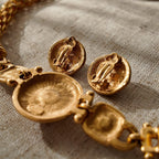 A detailed photo of the authentic Anne Klein signatures: the iconic lion head logo hang tag on the necklace and the signature "AK" hammered texture on the reverse.