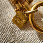 A detailed photo of the authentic Anne Klein signatures: the iconic lion head logo hang tag on the necklace and the signature "AK" hammered texture on the reverse.